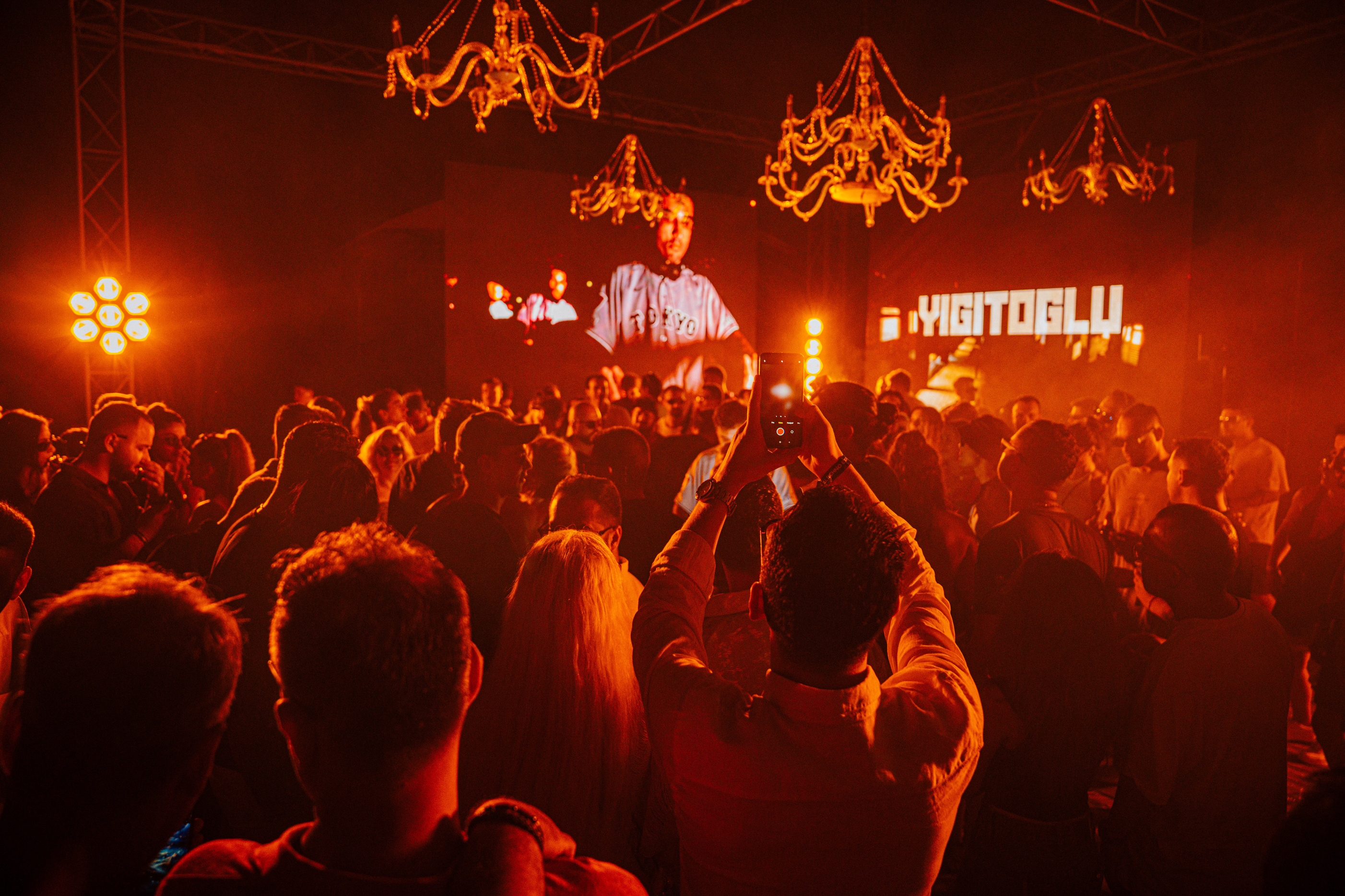 Yigitoglu performing under crystal chandeliers, name on the LED wall